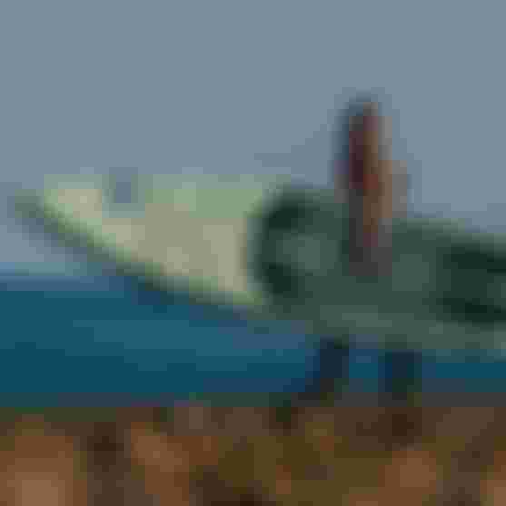 Girl carrying the SUP Board Raven Air SLS at the beach