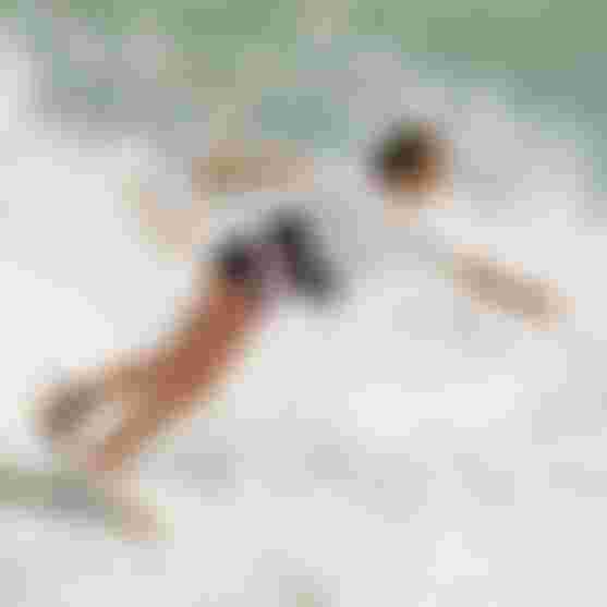 Camille Losserand kiteboarding skillfully on the ocean, creating splashes as she navigate the waves.