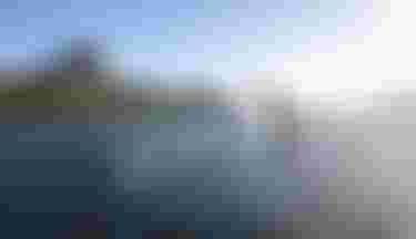 Two Kitesurfers in front of a mountain with clear blue sky
