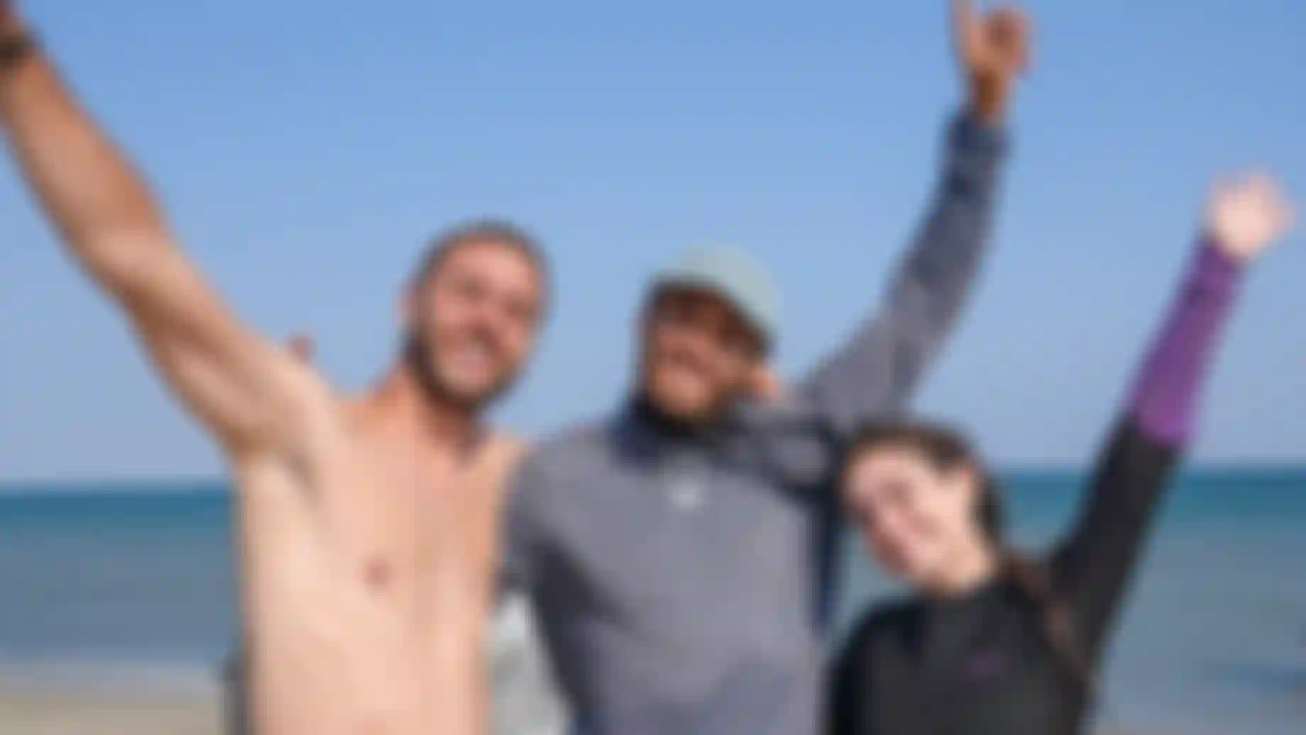 three people standing on the beach