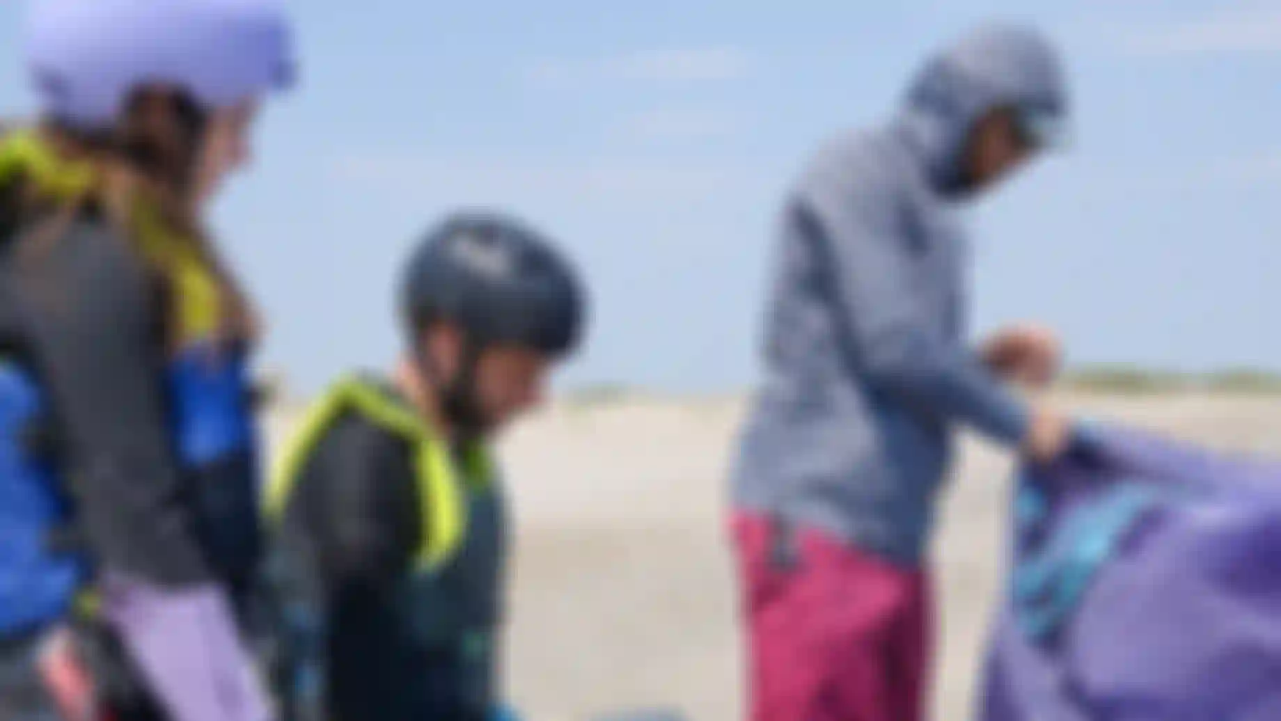 Three people looking at a kite on the beach