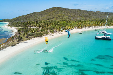 Duotone Dice LEI kite during kitesurfing at a tropical Caribbean-style beach with turquoise lagoon and palm trees