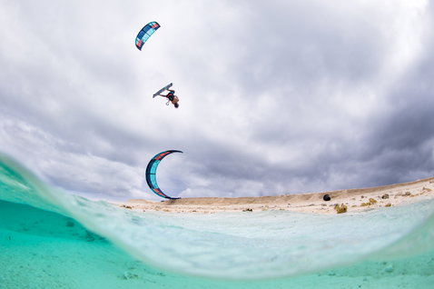 Duotone Rebel LEI kite durante el kitesurf en una playa de laguna tropical con dunas de arena blanca