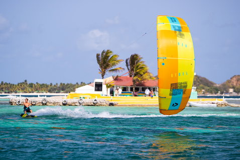 Duotone Rebel LEI kite durante el kitesurf en una laguna tropical con orilla de arena y palmeras