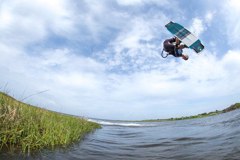 Duotone Team Series Hadlow TS tabla de kitesurf twin-tip durante kitesurf en laguna costera con orilla herbosa