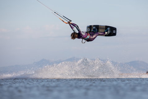 Duotone Team Series tabla de kitesurf twin-tip durante el kitesurf en una laguna con montañas de fondo