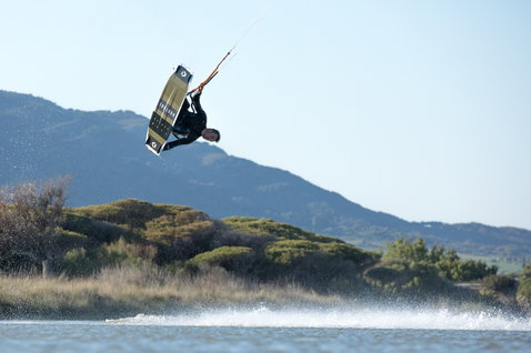 Tabla de kitesurf twin-tip Duotone Team Series durante el kitesurf en una laguna costera con montañas