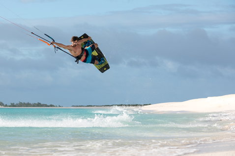 Duotone Select Textreme kiteboard twin-tip durante il kitesurf su una spiaggia tropicale