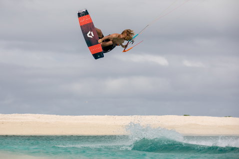 Duotone Select kiteboard twin-tip durante il kitesurf in una laguna tropicale con spiaggia di sabbia bianca