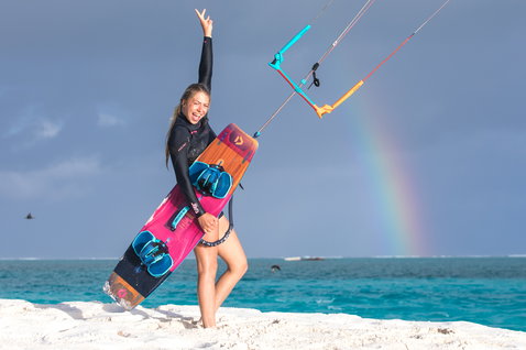 Duotone Soleil Twin-Tip Kiteboard beim Kitesurfen an einem tropischen Strand mit weißem Sand und türkisem Meer