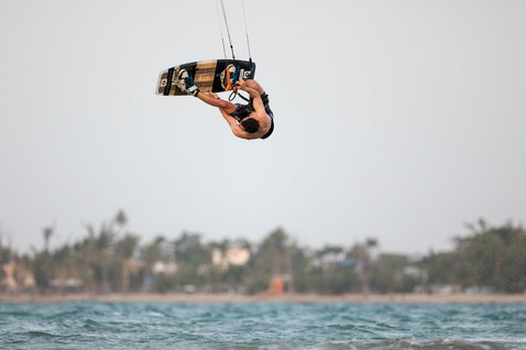 Duotone Team Series TS tabla de kitesurf twin-tip durante el kitesurf en una playa tropical con palmeras