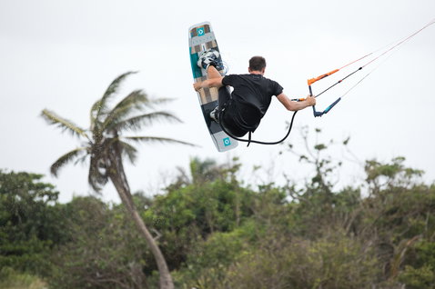 Duotone Team Series Hadlow TS tabla de kitesurf twin-tip 140cm durante el kitesurf en costa tropical con palmeras
