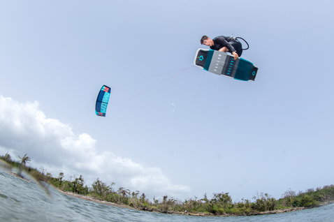 Duotone Team Series Hadlow tabla de kitesurf twin-tip durante el kitesurf en el océano con costa tropical