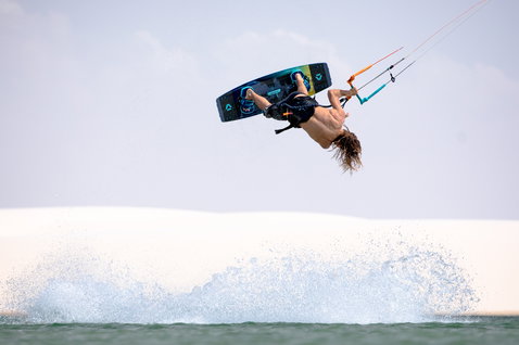 Duotone Trust Bar Quad Control Control Bar beim Kitesurfen an einem Ozeanstrand mit weißen Sanddünen