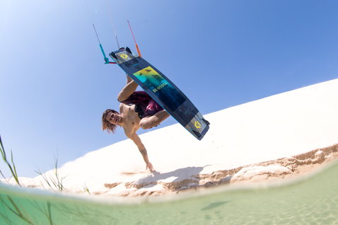 Duotone Jaime kiteboard twin-tip lors du kitesurf sur plage tropicale avec dunes blanches et lagon peu profond