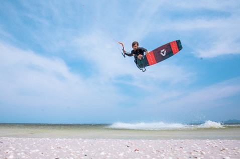 Duotone Select twin-tip kiteboard durante il kitesurf nell'oceano su una spiaggia tropicale