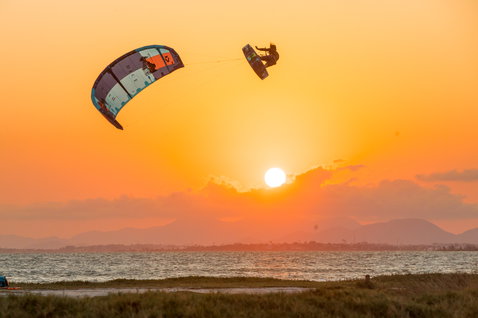 Duotone Dice LEI kite during kitesurfing at the coastal beach with mountains on the horizon