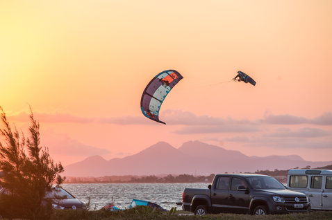 Duotone Dice LEI kite during kitesurfing on an ocean beach with mountains in the background