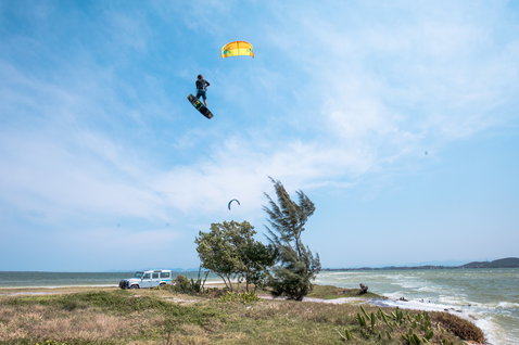 Duotone Evo LEI kite during kitesurfing at coastal beach with vegetation and ocean shoreline