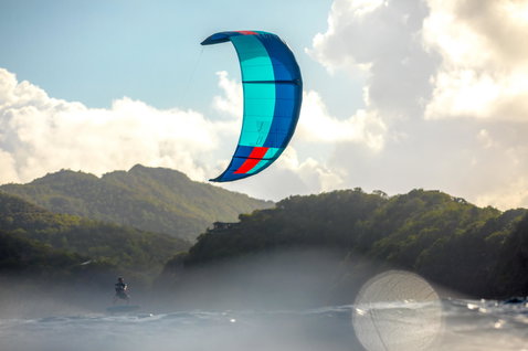 Duotone Juice LEI Kite beim Kitesurfen in einer Küstenbucht mit bewaldeten Hügeln