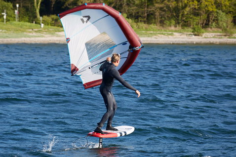 Duotone X Foil Wing 2019 ala de foil durante el wing foiling en un lago interior con orilla arbolada