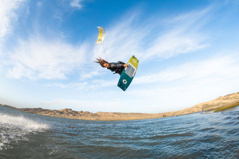 Duotone Rebel LEI kite durante il kitesurf in una laguna costiera con dune di sabbia