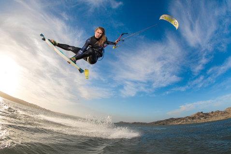 Duotone Rebel LEI kite durante il kitesurf su una laguna in acque aperte con colline aride in lontananza