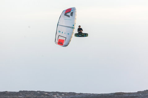 Duotone Dice LEI Kite beim Kitesurfen an einer felsigen Küste unter offenem Himmel