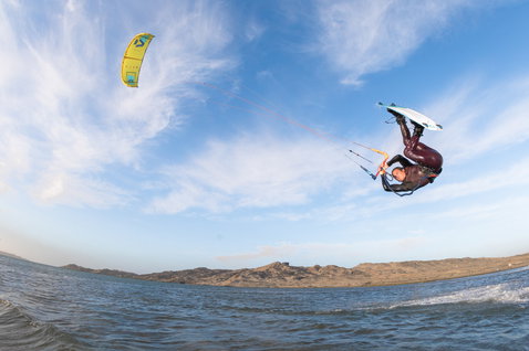 Duotone Dice LEI Kite beim Kitesurfen an einer Meeresküste mit kargen Hügeln