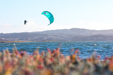 Duotone Dice LEI Kite beim Kitesurfen in einer Küstenlagune mit Hügeln im Hintergrund
