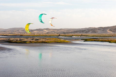 Duotone Dice LEI Kite beim Kitesurfen in einer Gezeitenlagune mit Sanddünen und Bergen im Hintergrund