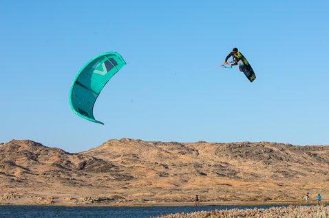 Duotone Dice LEI Kite beim Kitesurfen an einer kargen Küstenlagune mit Sanddünen