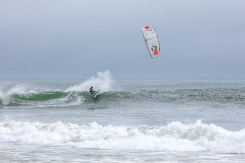 Duotone Dice LEI Kite 7m beim Wellenreiten am Ozeanstrand mit offener See und brechenden Wellen