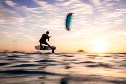 Foil kiteboard lors du foiling en mer ouverte au coucher du soleil