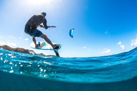 Foil kiteboard lors du foiling sur l'océan tropical avec littoral rocheux