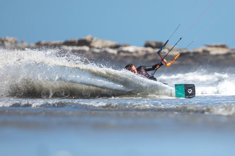 Duotone Click Bar Quad Control control bar during kitesurfing at an ocean coastline with rocky shore