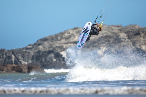 Duotone Trust Bar Quad Control Kontrollbar beim Kitesurfen an einer felsigen Meeresküste