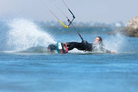 Duotone Trust Bar Quad Control Steuerbar beim Kitesurfen in einer flachen Bucht mit Felsenmole