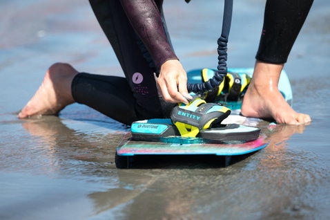 Duotone Entity Ergo tabla de kitesurf twin-tip en carbón oscuro con teal, amarillo verde y rosa
