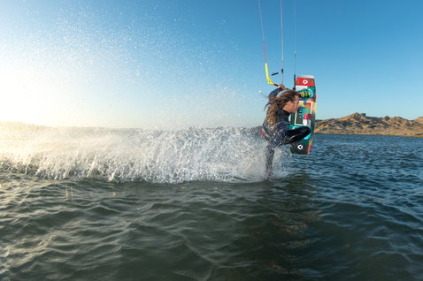 Duotone Jaime Twin-Tip Kiteboard beim Kitesurfen auf einem See mit Bergkulisse