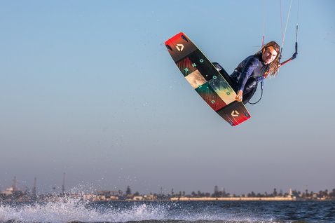 Duotone Jaime Twin-Tip Kiteboard beim Kitesurfen in einer Küstenbucht mit Skyline
