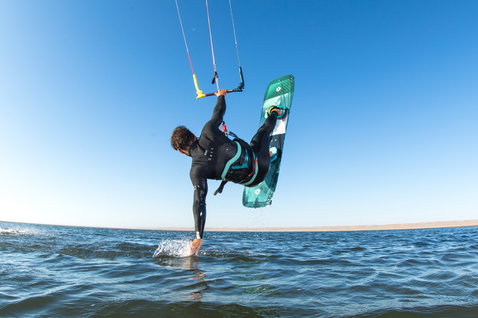 Duotone Ultraspike kiteboard twin-tip lors du kitesurf en océan ouvert avec plage de sable en arrière-plan