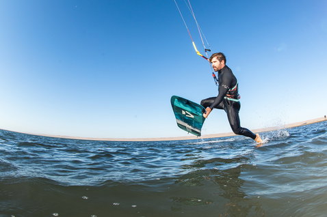Duotone Ultraspike kiteboard twin-tip 165cm lors d'une session de kitesurf sur eau plate avec plage de sable en arrière-plan