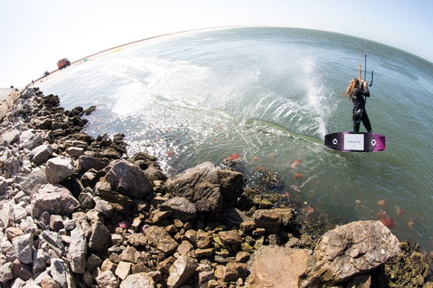 Duotone Soleil Textreme twin-tip kiteboard during kitesurfing at a coastal rocky breakwater