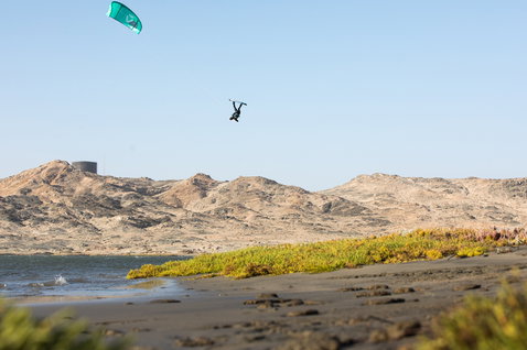 Duotone Gambler tavola da kitesurf wake-style durante wakestyle kitesurf su una spiaggia costiera con laguna