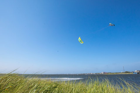 Duotone Vegas LEI kite during kitesurfing at a coastal lagoon with grassy dunes and flat water