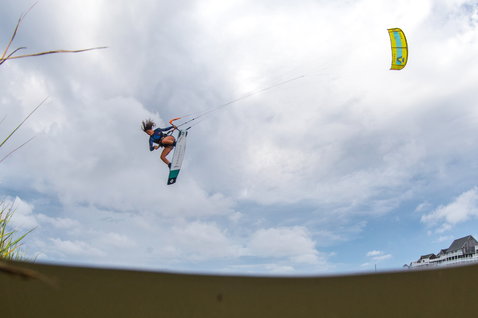 Duotone Vegas LEI kite during kitesurfing on a coastal waterway near a beach with buildings and grass