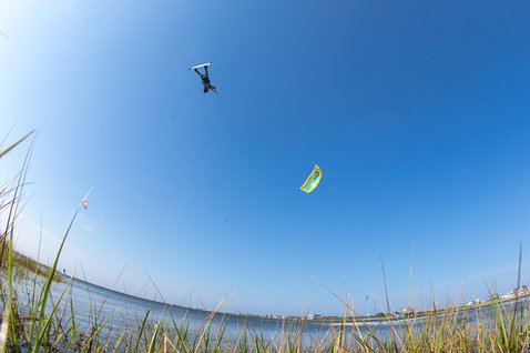 Tabla de kitesurf twin-tip Duotone Team Series Textreme TS durante el kitesurf en una laguna costera con orilla herbosa y agua abierta
