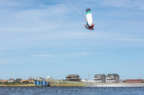 Duotone Team Series Textreme tabla de kitesurf twin-tip durante kitesurf en laguna costera con casas de playa