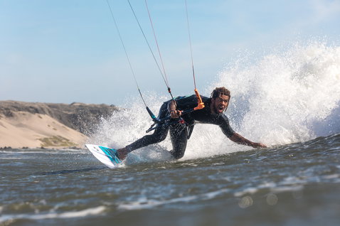 Duotone Pro Session 2020 kiteboard direzionale durante il kitesurf su spiaggia oceanica con dune di sabbia